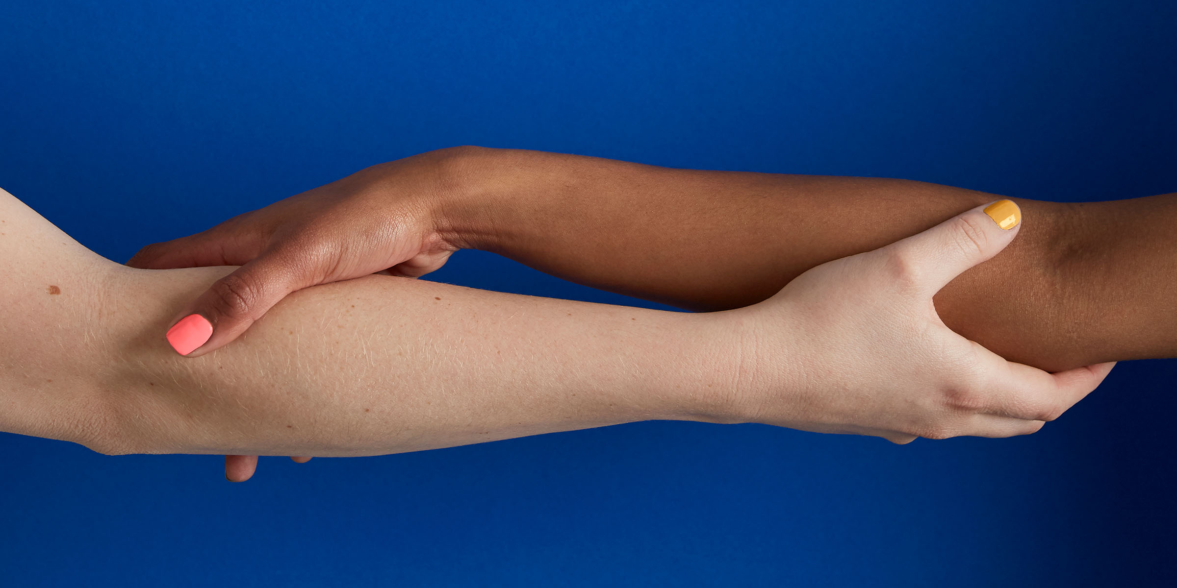 A closely cropped shot of two women with their arms intertwined